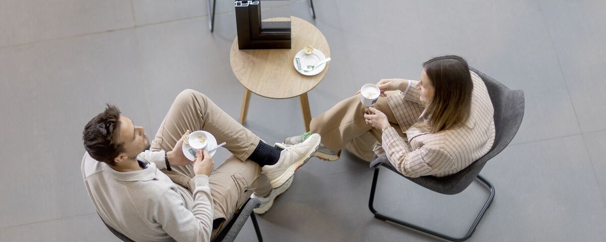 Top view man and woman sitting at table drinking coffee.