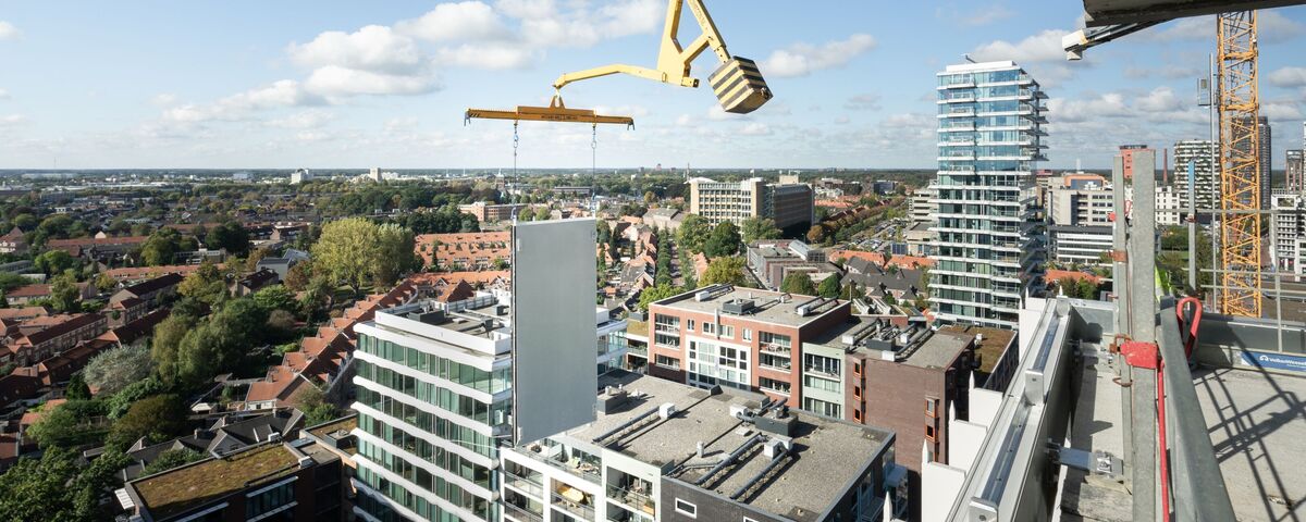 Modular building panel lifted next to skyscraper.